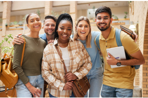 Grupo de cinco jovens sorridentes, de diferentes etnias, posando juntos em um ambiente escolar ou universitário. Eles usam roupas casuais e carregam mochilas e cadernos, transmitindo uma atmosfera de amizade, diversidade e ambiente acadêmico