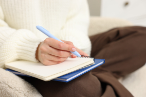 Pessoa escrevendo em planner ou caderno de estudos, organizando a rotina de forma manual.